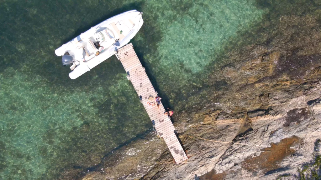 Vue drone d’un bateau amarré à un ponton, entre mer calme et lumière naturelle, évoquant l’art de vivre en Provence.